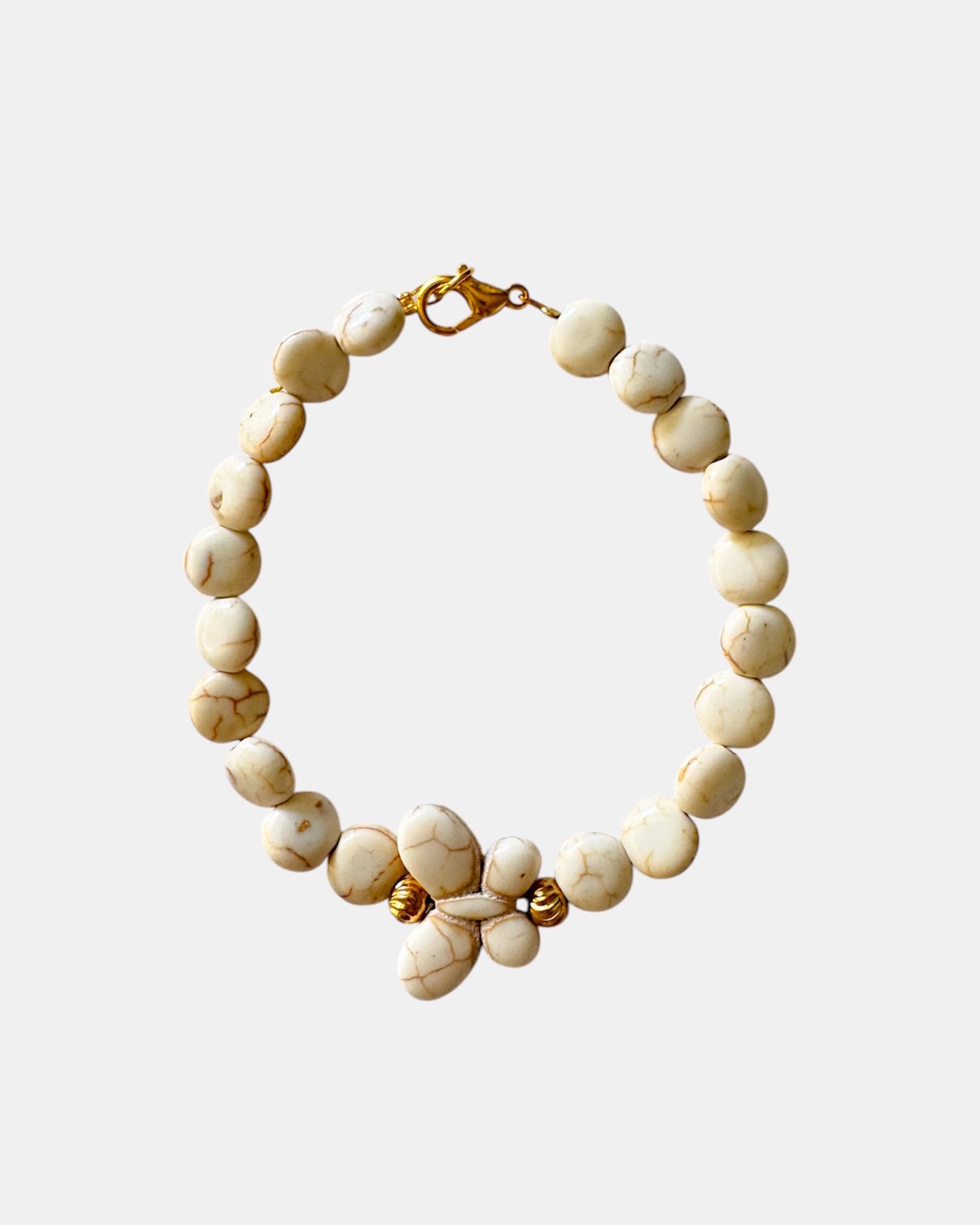 Beige beaded bracelet with a decorative butterfly charm