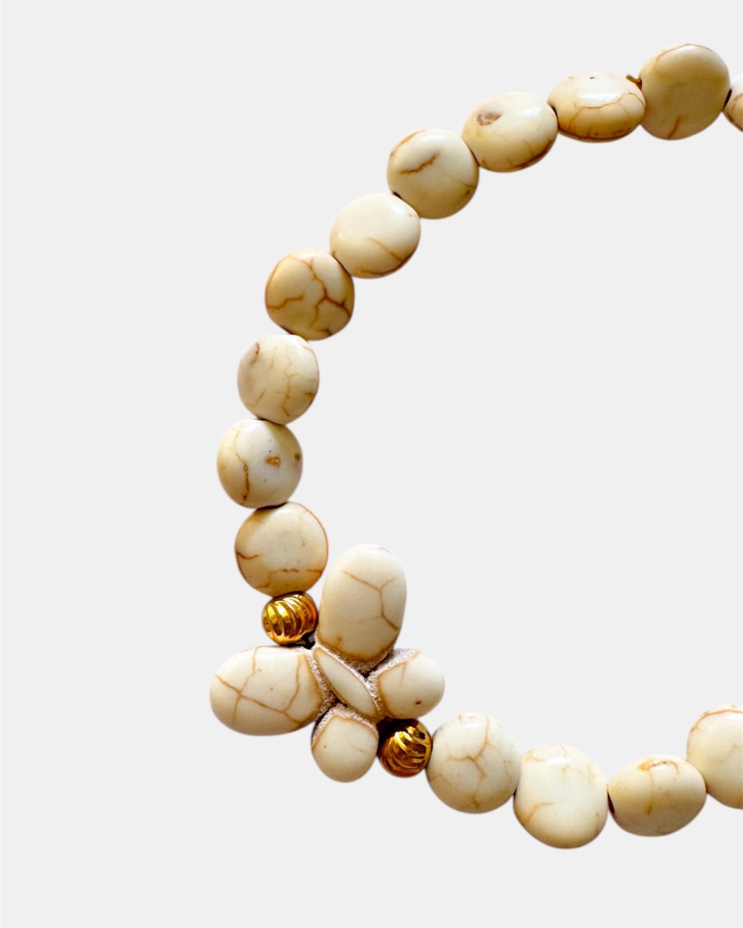 Beige beaded bracelet with a decorative butterfly charm
