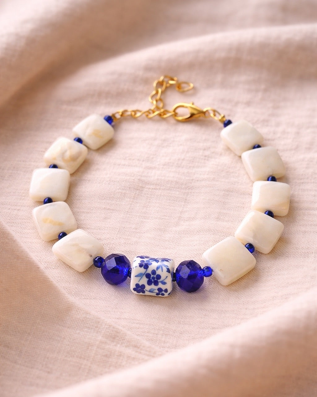 Beige bracelet featuring mother-of-pearl and a blue ceramic charm for a natural and elegant style