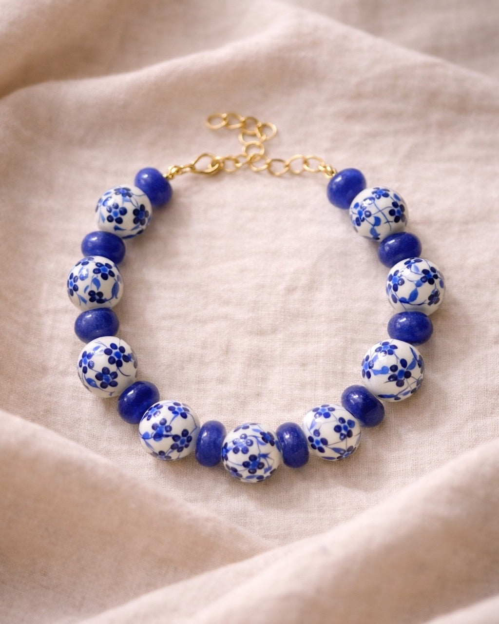 Bracelet with blue and white floral beads on a beige fabric background