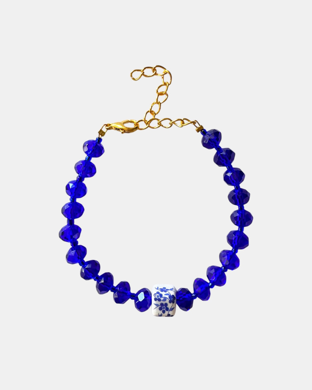 Blue bracelet featuring glass beads and a ceramic charm for a stylish, artistic look