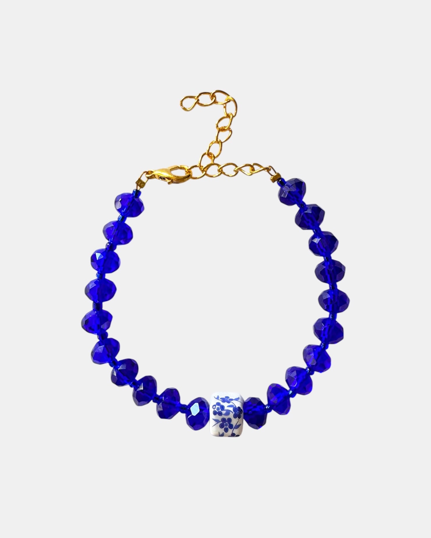 Blue bracelet featuring glass beads and a ceramic charm for a stylish, artistic look
