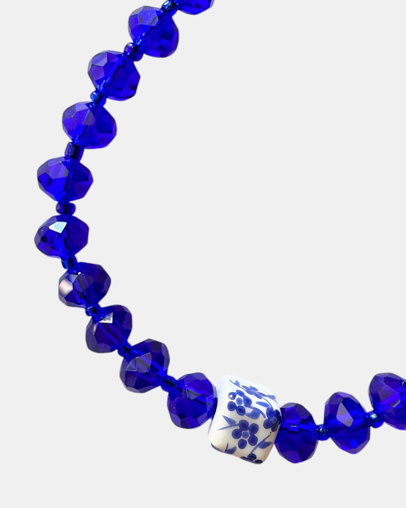Blue bracelet featuring glass beads and a ceramic charm for a stylish, artistic look