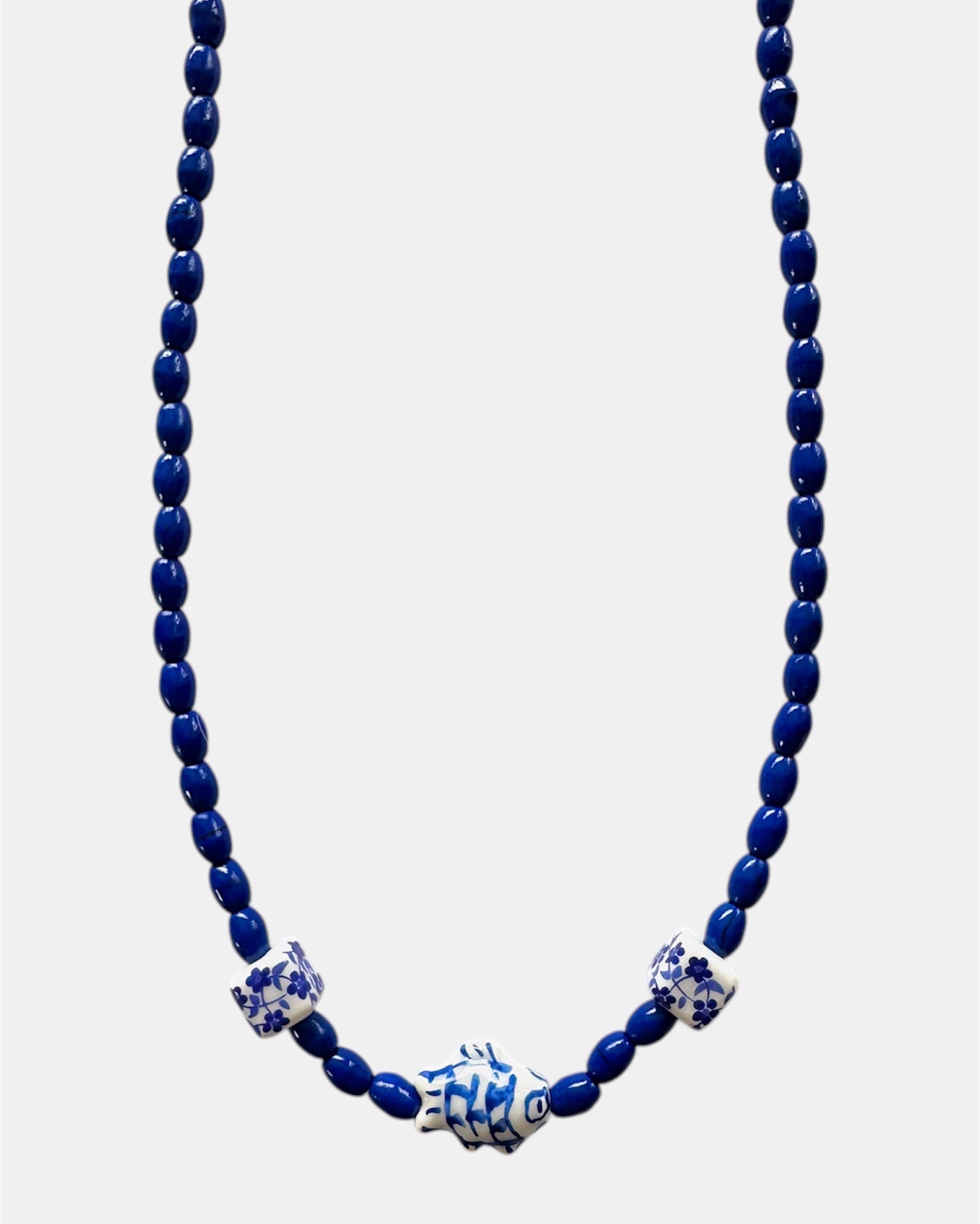 Blue beaded necklace with decorative elements on a white background