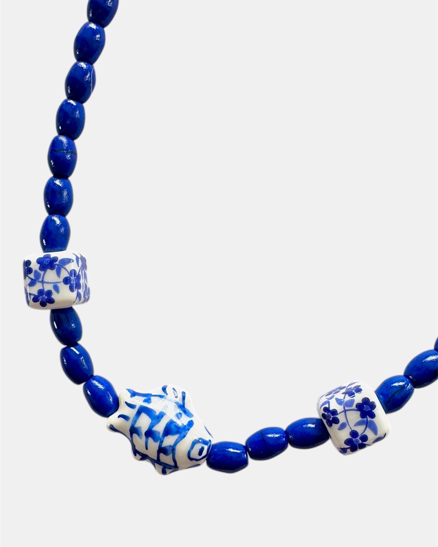 Blue beaded necklace with decorative elements on a white background
