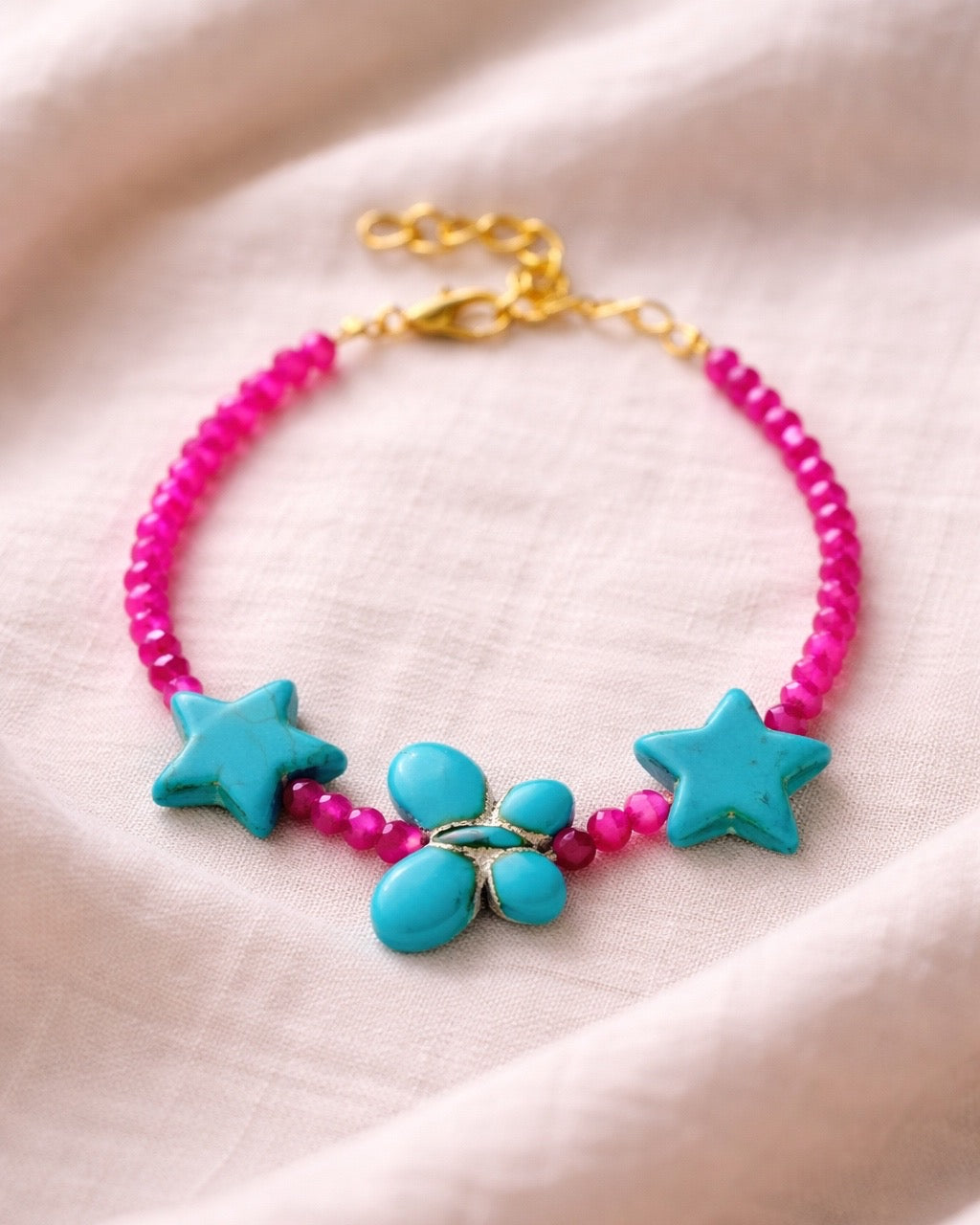 Fuchsia bracelet decorated with turquoise star charms and a butterfly for a whimsical, playful style
