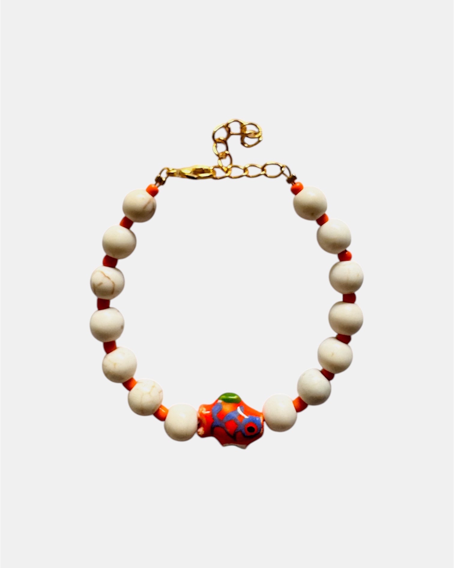 Elegant gold bracelet with ecru beads and ceramic fish charm, handmade jewelry inspired by the sea with natural coastal style
