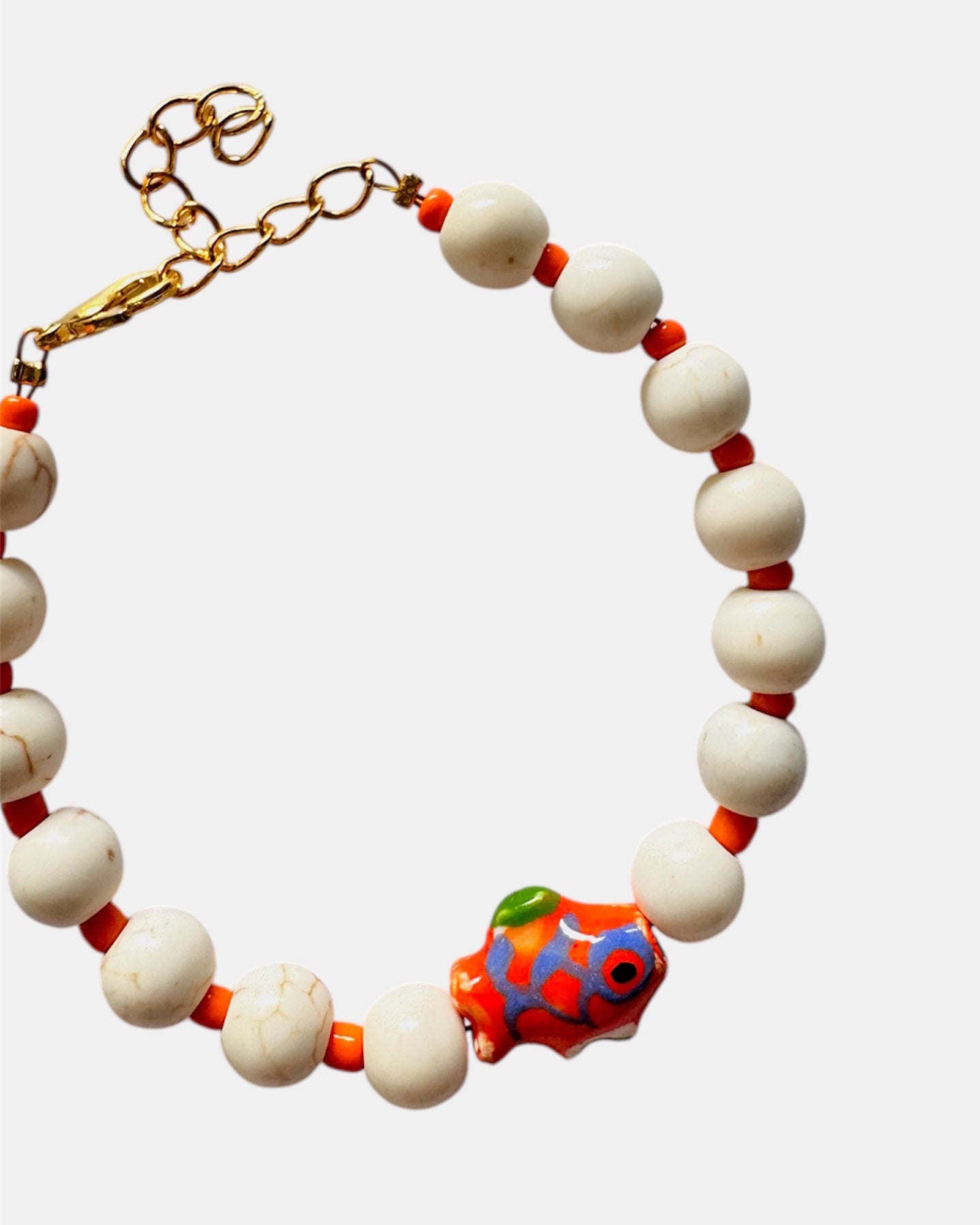 Elegant gold bracelet with ecru beads and ceramic fish charm, handmade jewelry inspired by the sea with natural coastal style