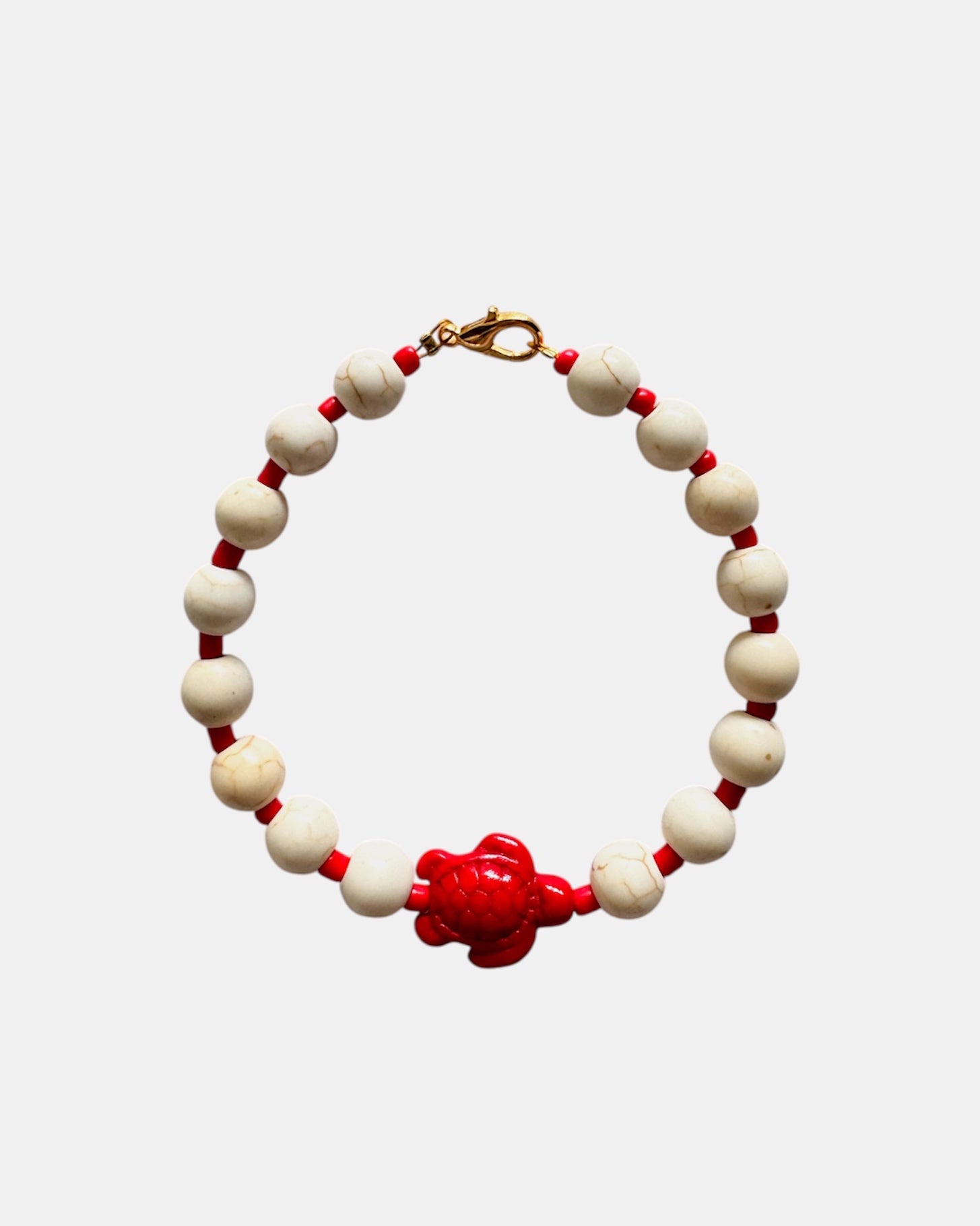 Elegant gold bracelet with ecru beads and ceramic turtle charm, handmade jewelry with natural tones inspired by the sea and coastal lifestyle