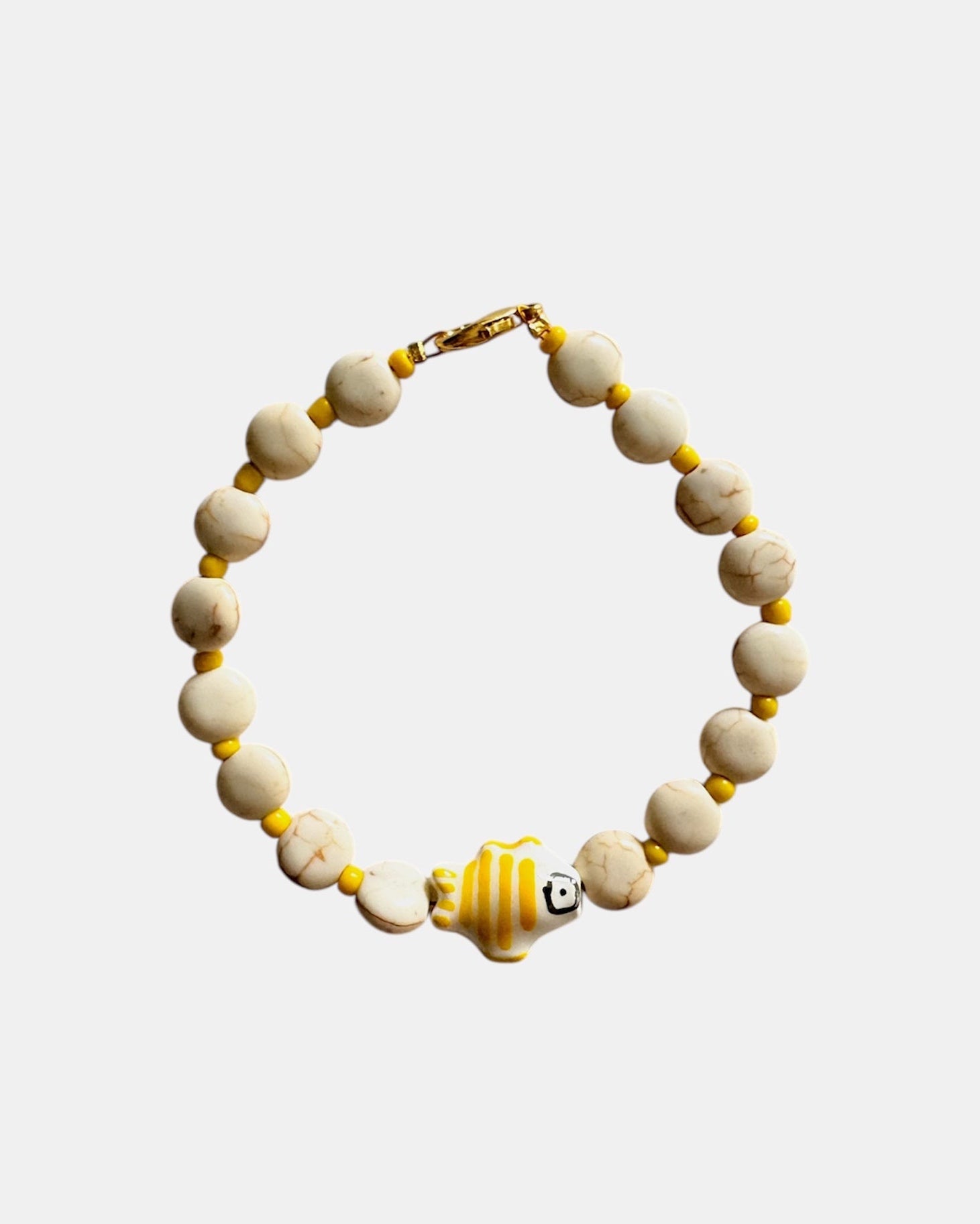 Elegant gold bracelet with ecru beads and fish charm, minimalist handmade jewelry inspired by the sea and coastal style