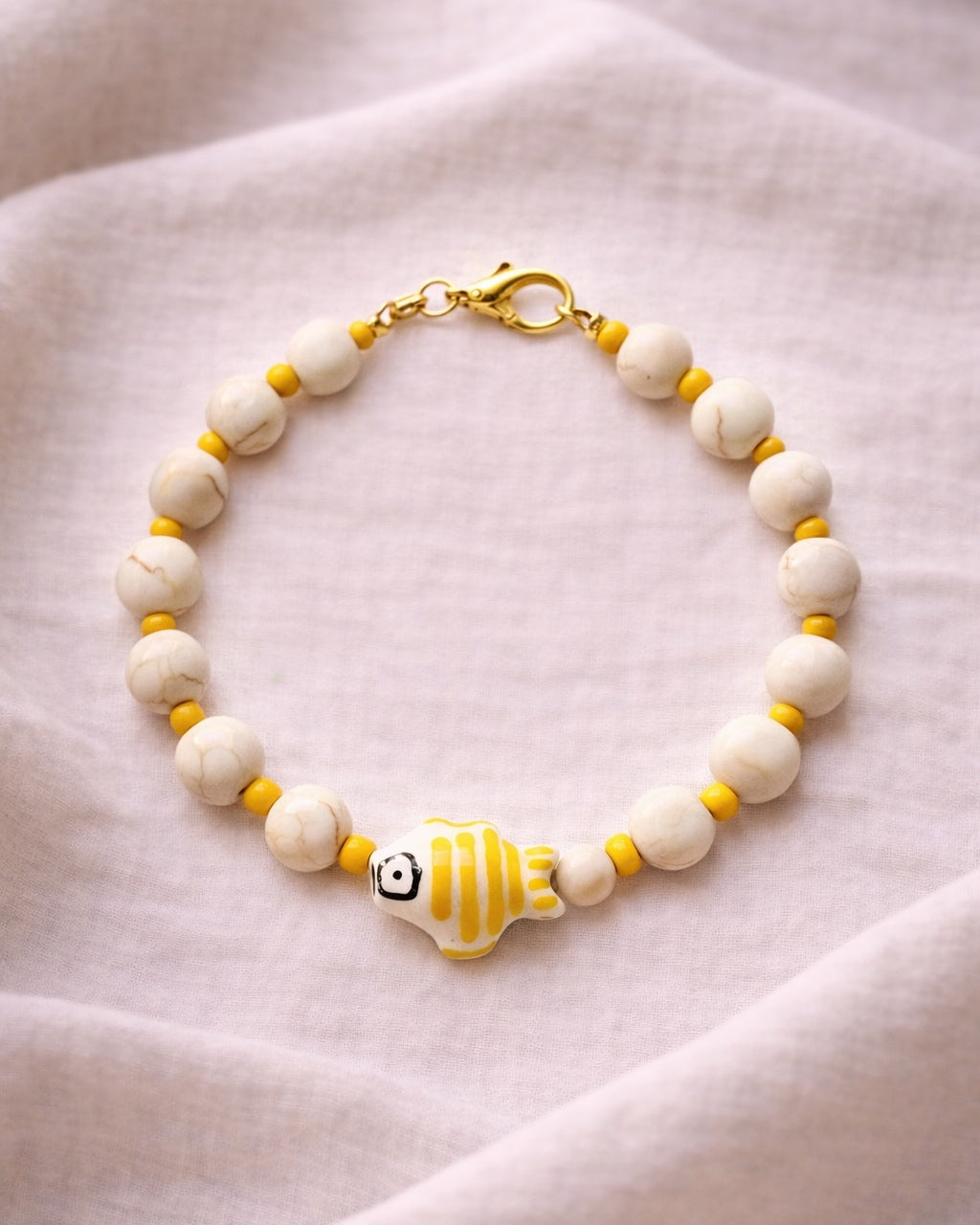 Elegant gold bracelet with ecru beads and fish charm, minimalist handmade jewelry inspired by the sea and coastal style