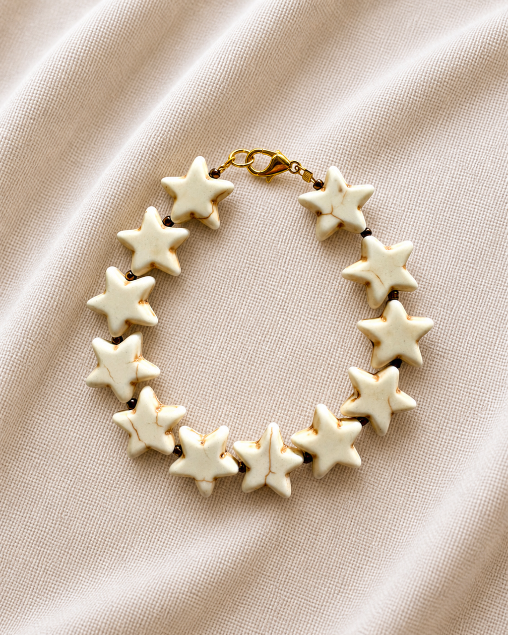 Gold bracelet with ecru star charms.