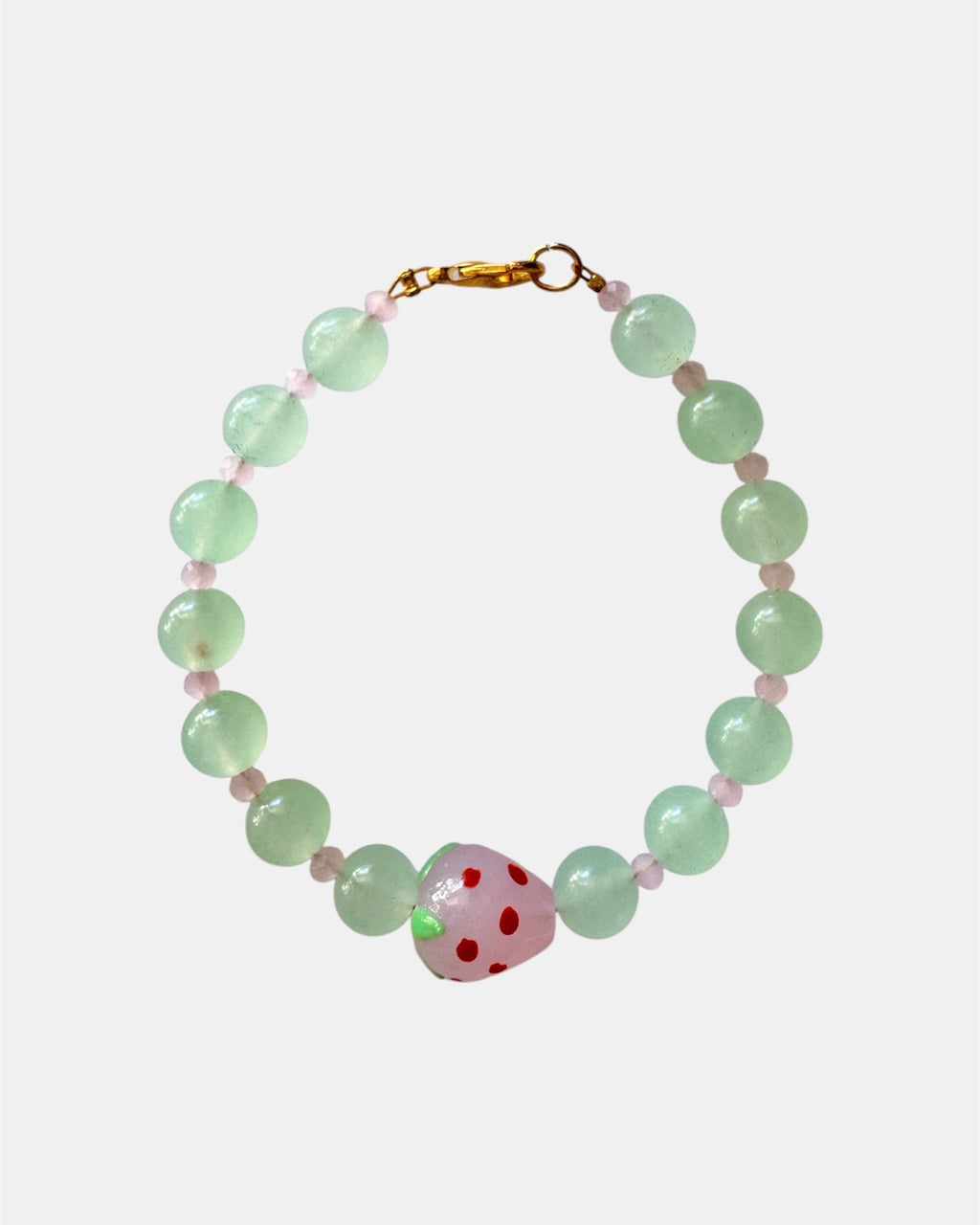 Gold bracelet with green beads and strawberry charm.