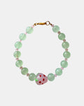 Gold bracelet with green beads and strawberry charm.