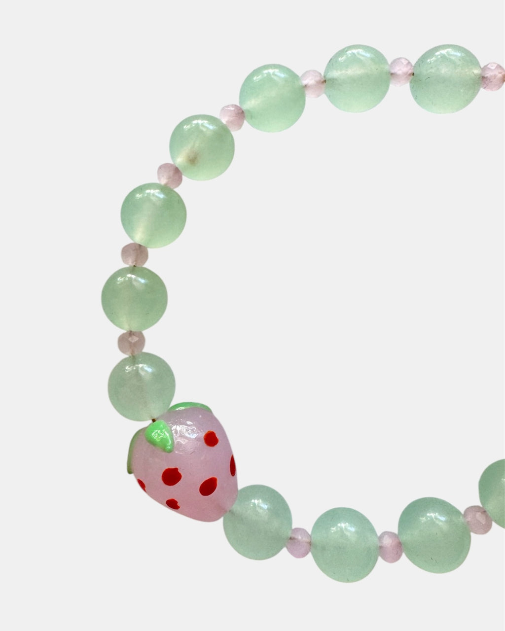 Gold bracelet with green beads and strawberry charm.