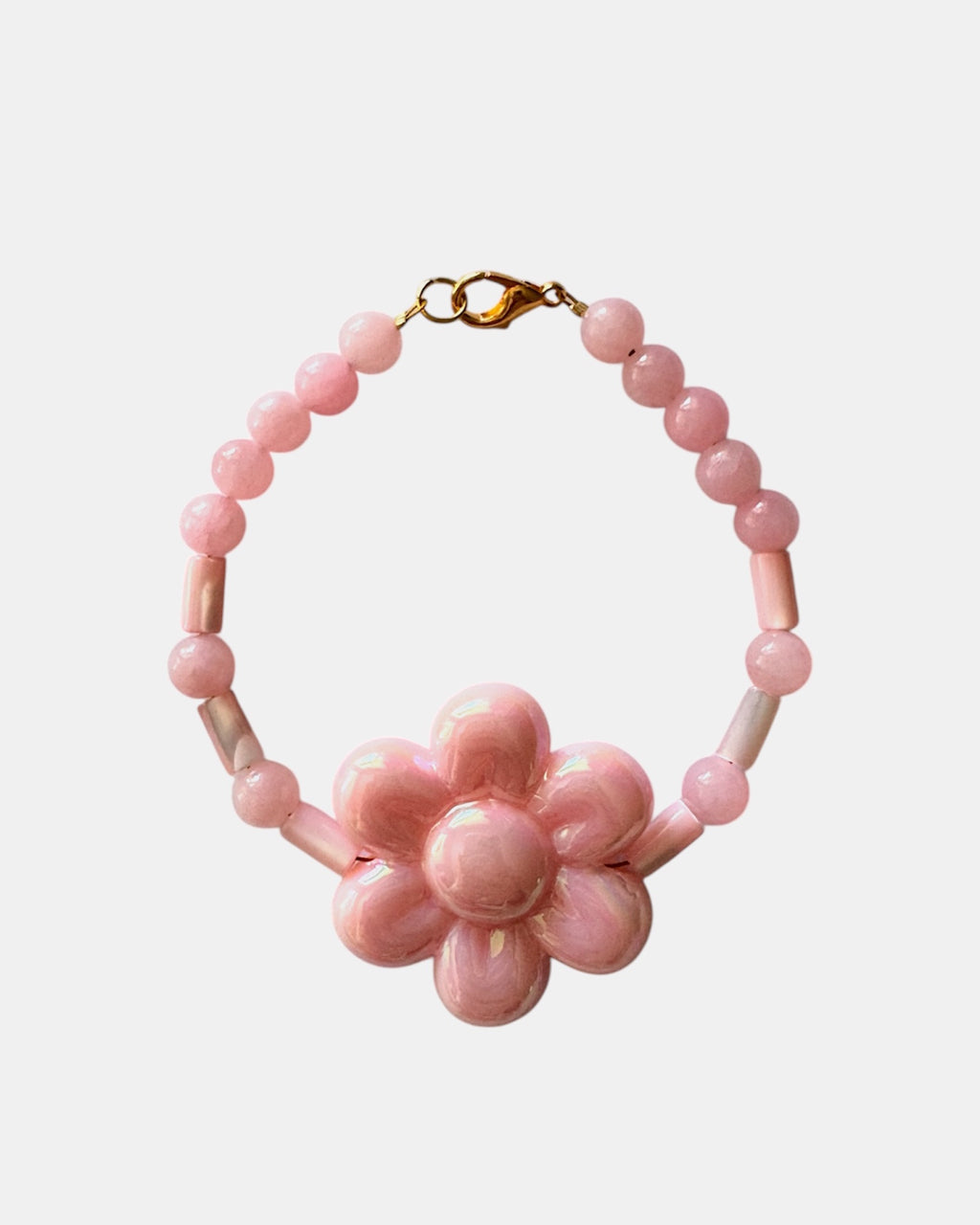 Gold bracelet with pink beads and a ceramic flower charm