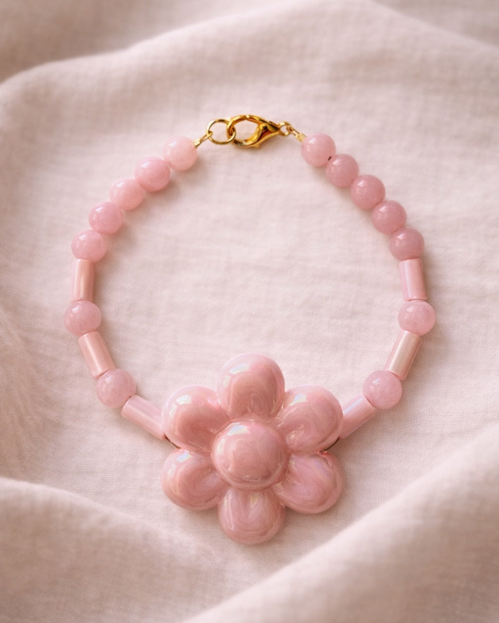 Gold bracelet with pink beads and a ceramic flower charm