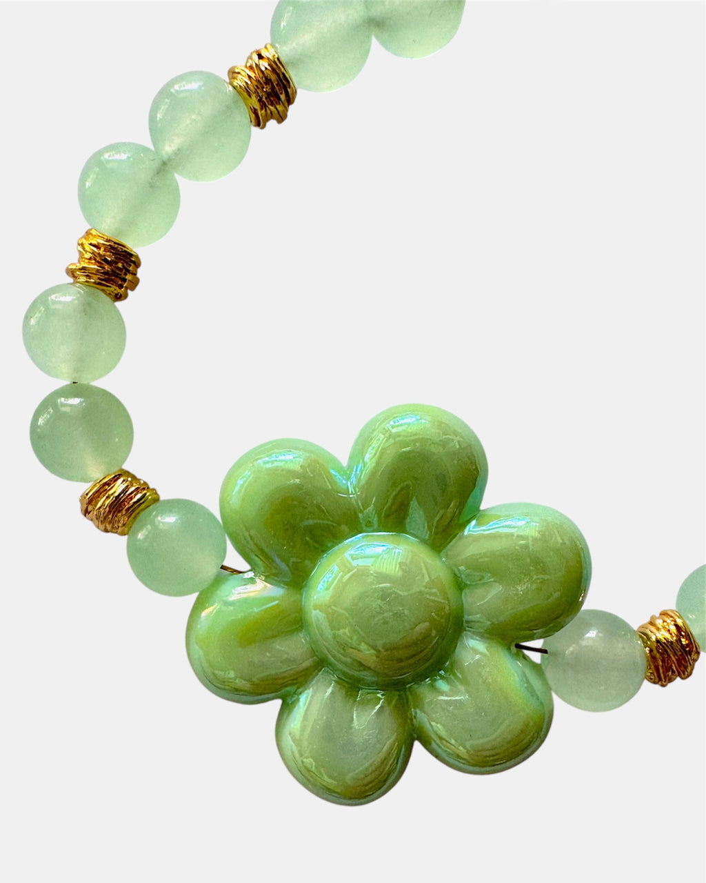 Gold bracelet with green beads and ceramic flower charm in elegant boho style