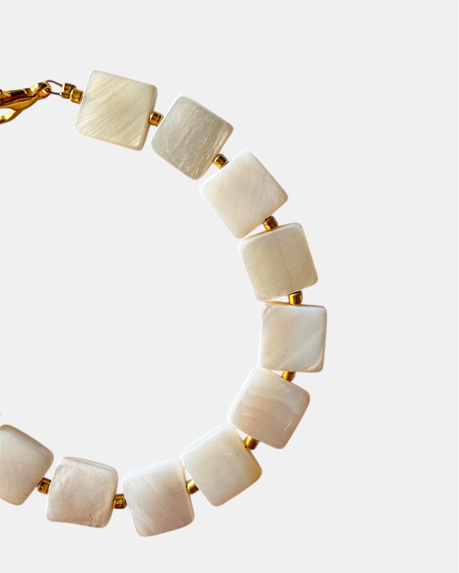 Necklace with white beads and gold accents on a light gray background
