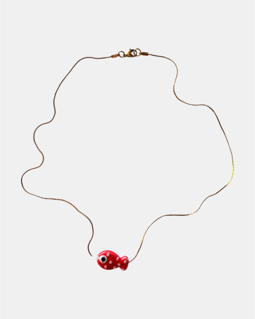 Gold chain necklace with a red fish charm
