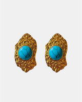 Gold dangling earrings with teal stone.