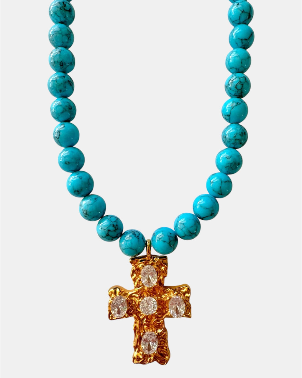Gold necklace with turquoise beads and a cross pendant.