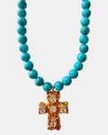 Gold necklace with turquoise beads and a cross pendant.