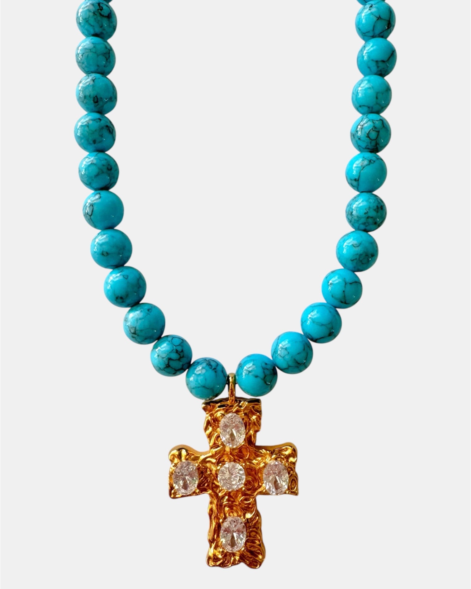 Gold necklace with turquoise beads and a cross pendant.