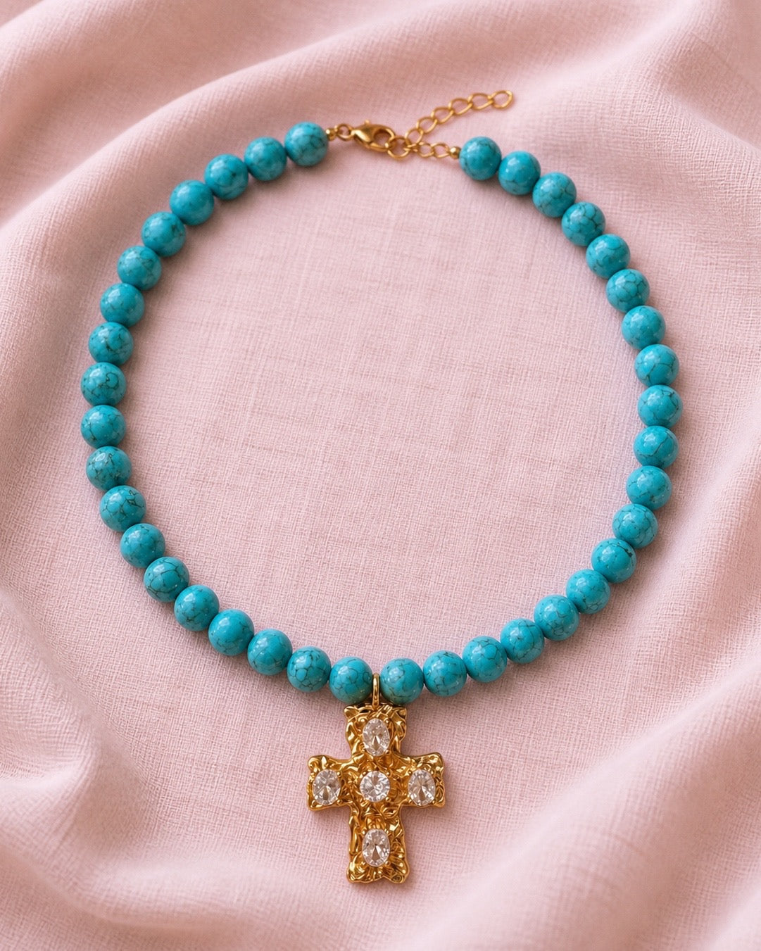 Gold necklace with turquoise beads and a cross pendant.