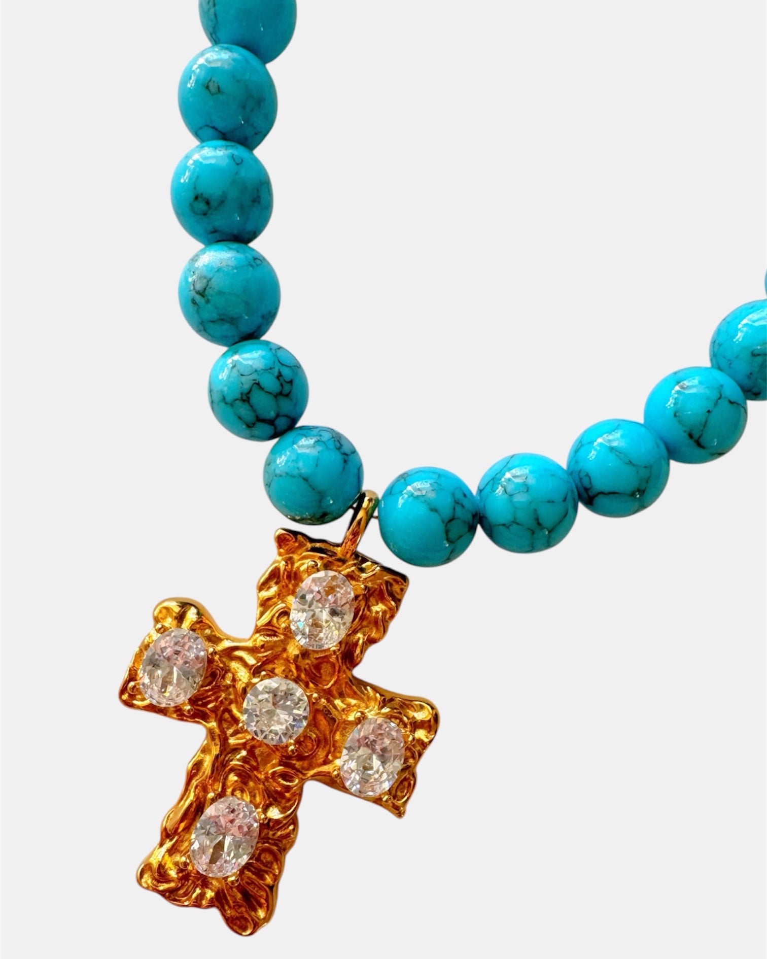 Gold necklace with turquoise beads and a cross pendant.