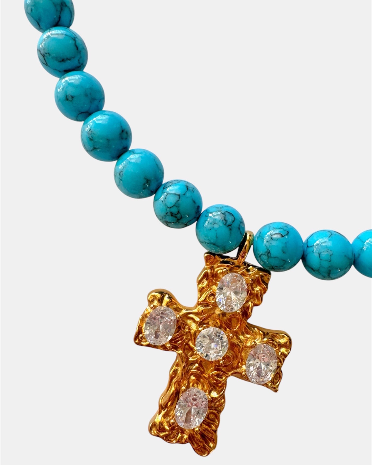 Gold necklace with turquoise beads and a cross pendant.