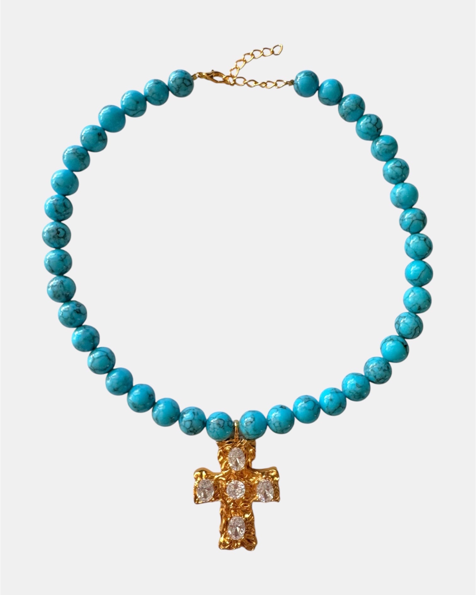 Gold necklace with turquoise beads and a cross pendant.