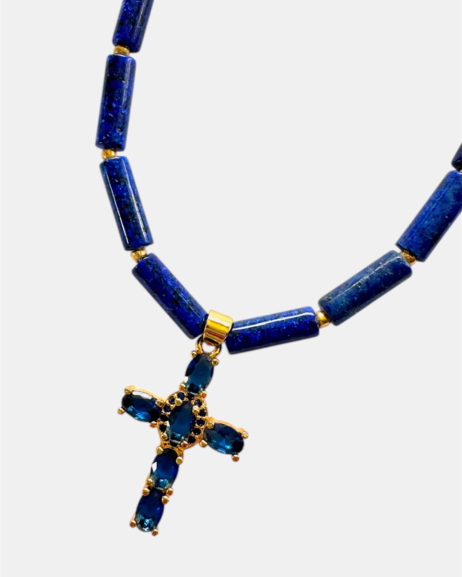 Necklace with blue beads and a gold cross pendant on a white background