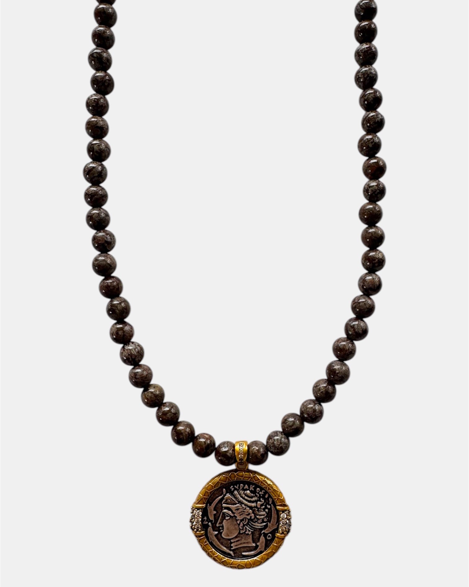 Necklace with dark beads and a decorative pendant on a white background