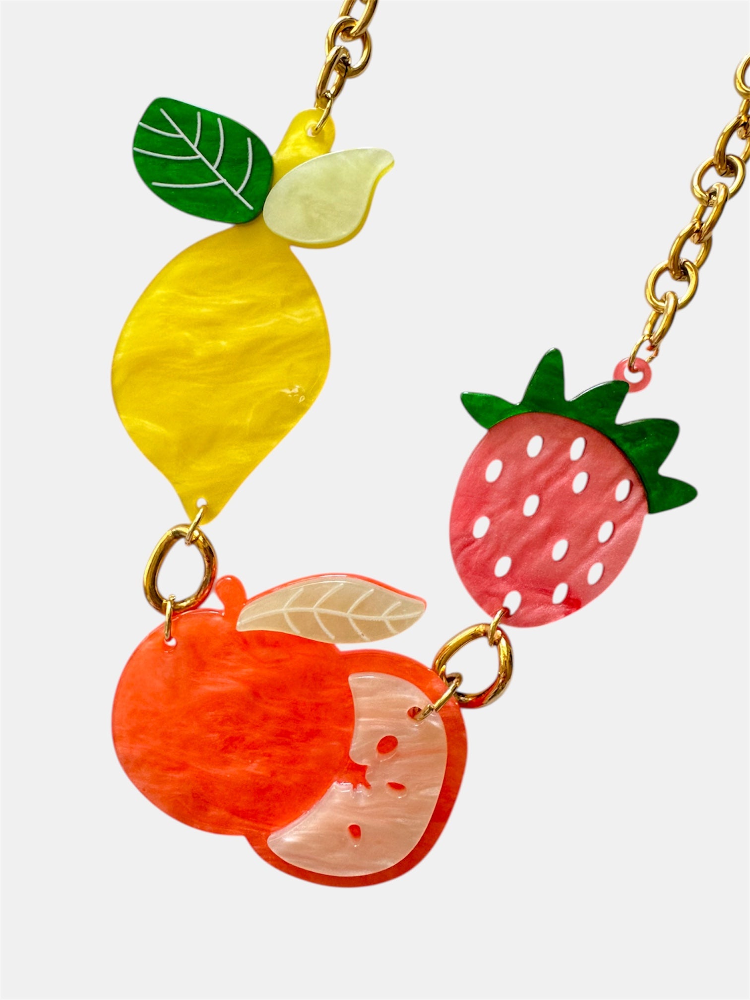 Gold necklace featuring small fruit-shaped charms for a playful and stylish look