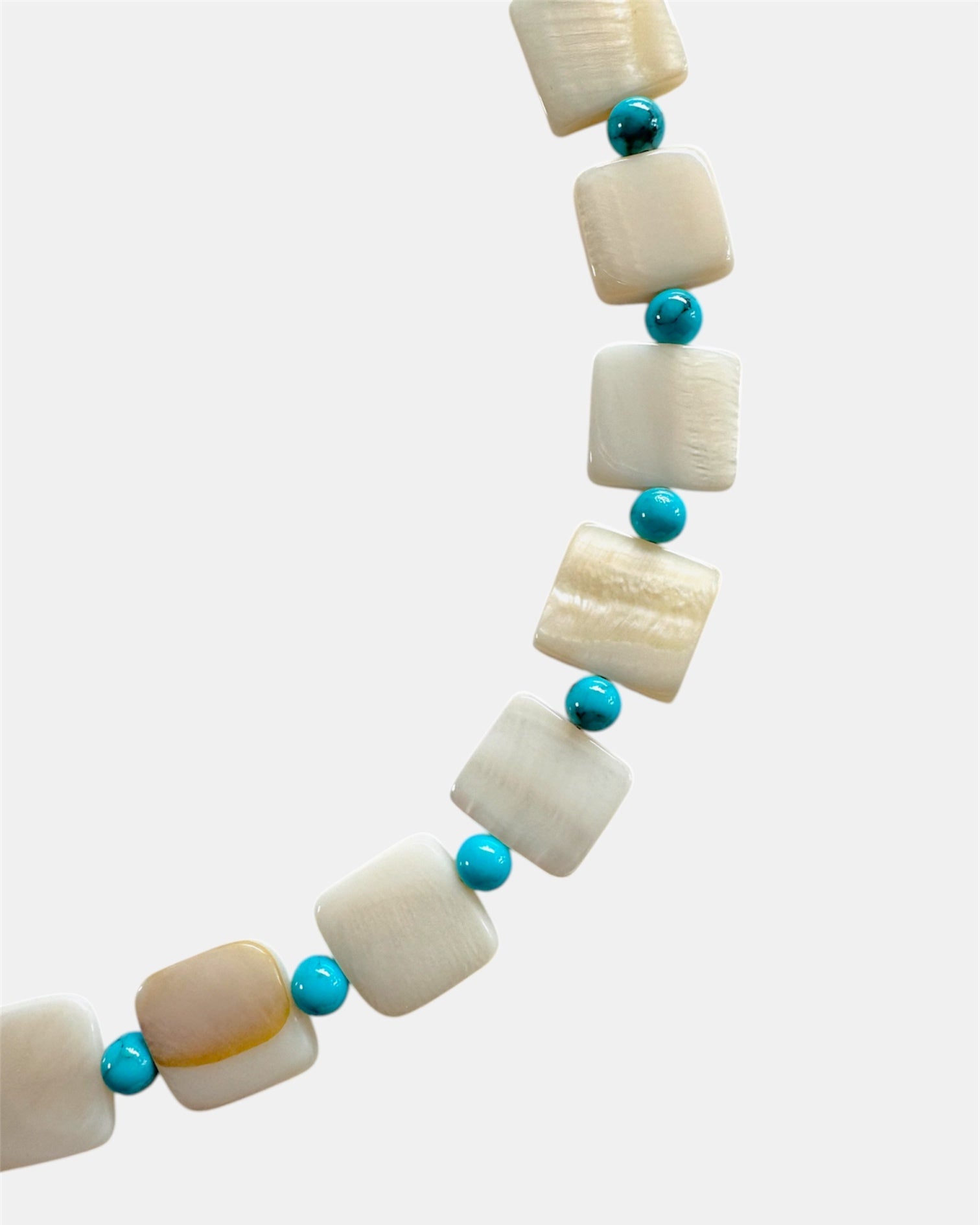 Necklace with white beads and turquoise stones on a white background