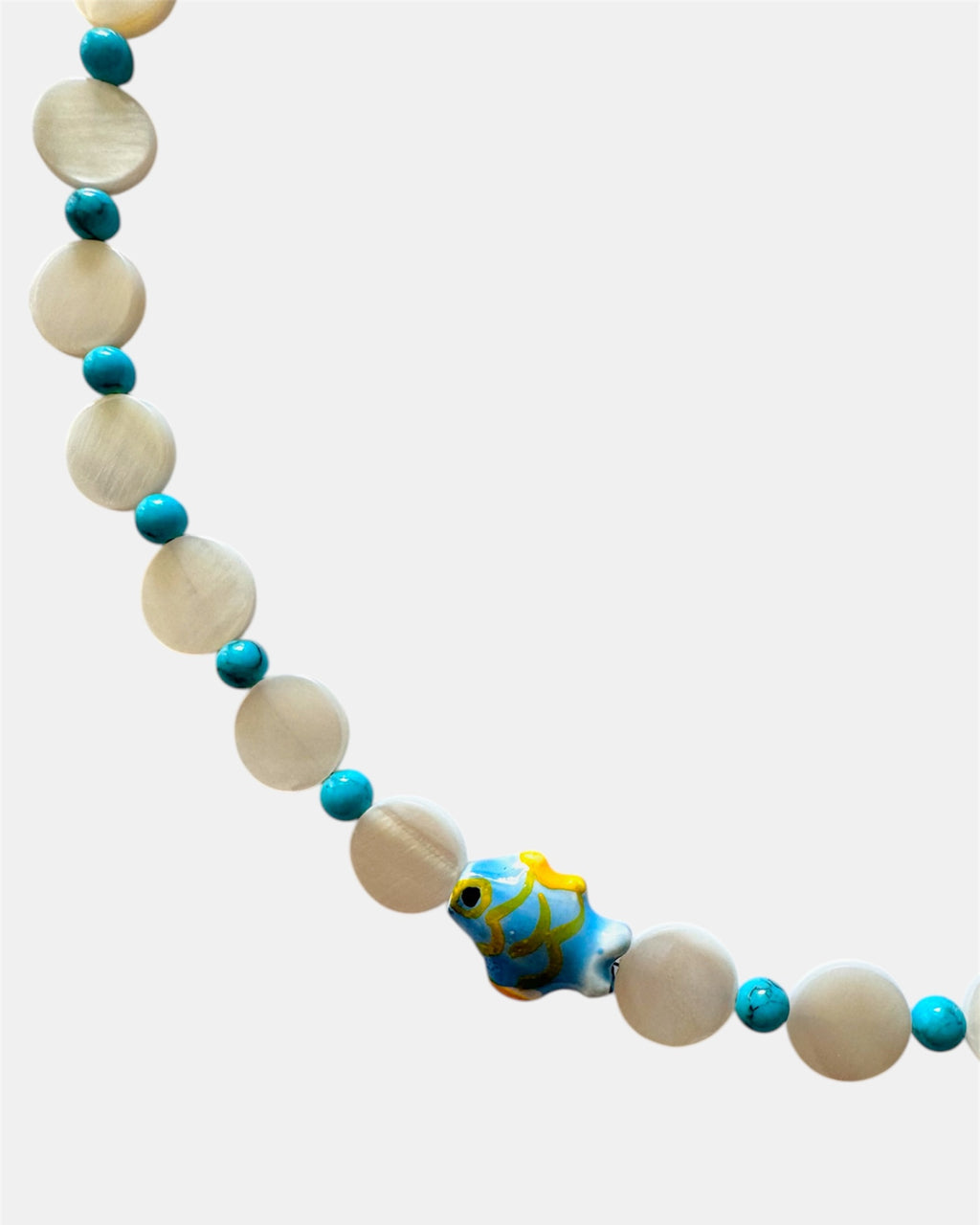 Necklace with white beads and blue accents featuring a fish-shaped charm on a white background