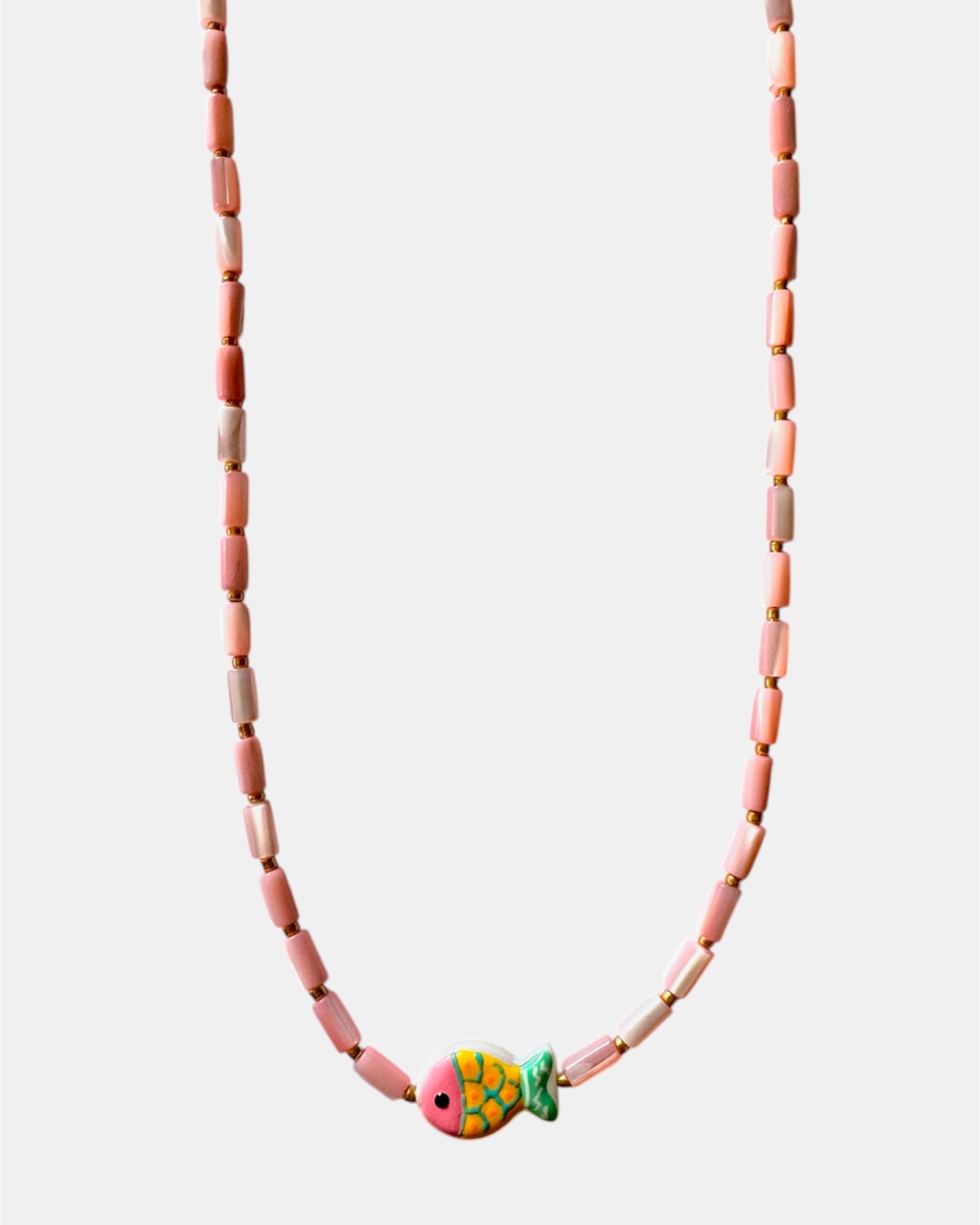 Necklace with pink beads and a colorful fish charm on a white background