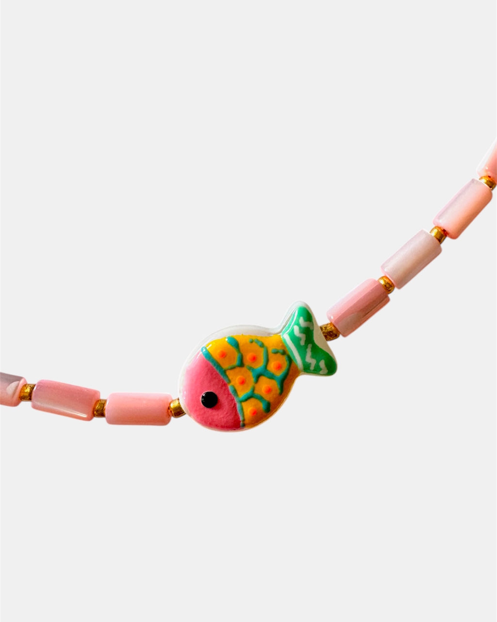 Necklace with pink beads and a colorful fish charm on a white background