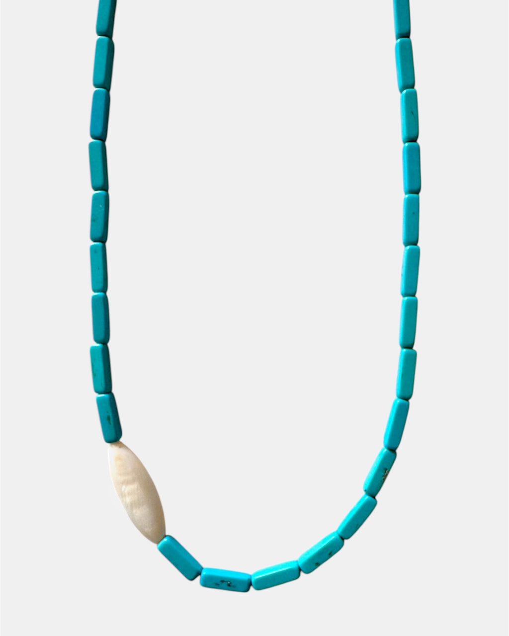Necklace with blue beads and a beige stone on a light gray background