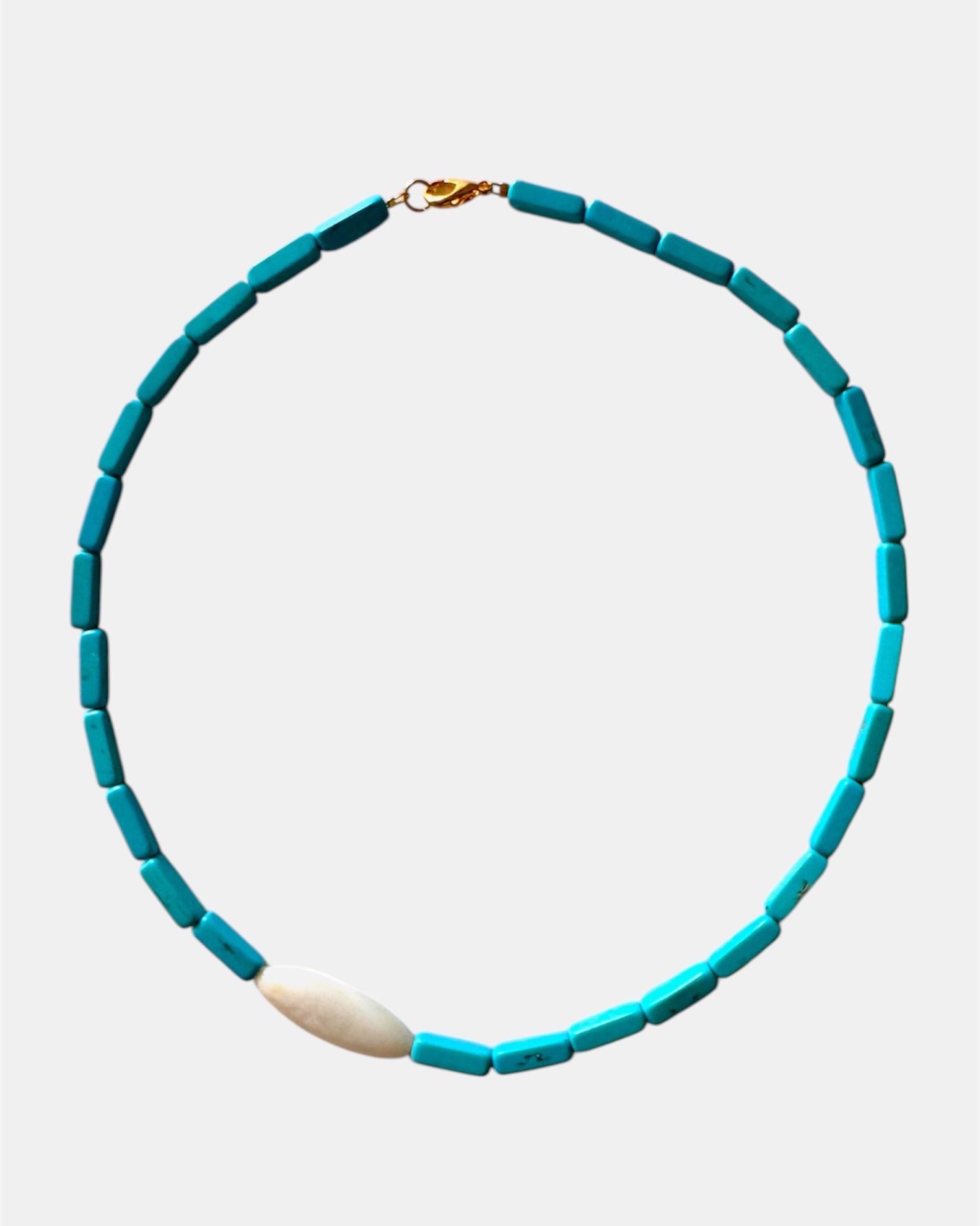Turquoise beaded necklace with a white pendant on a light gray background