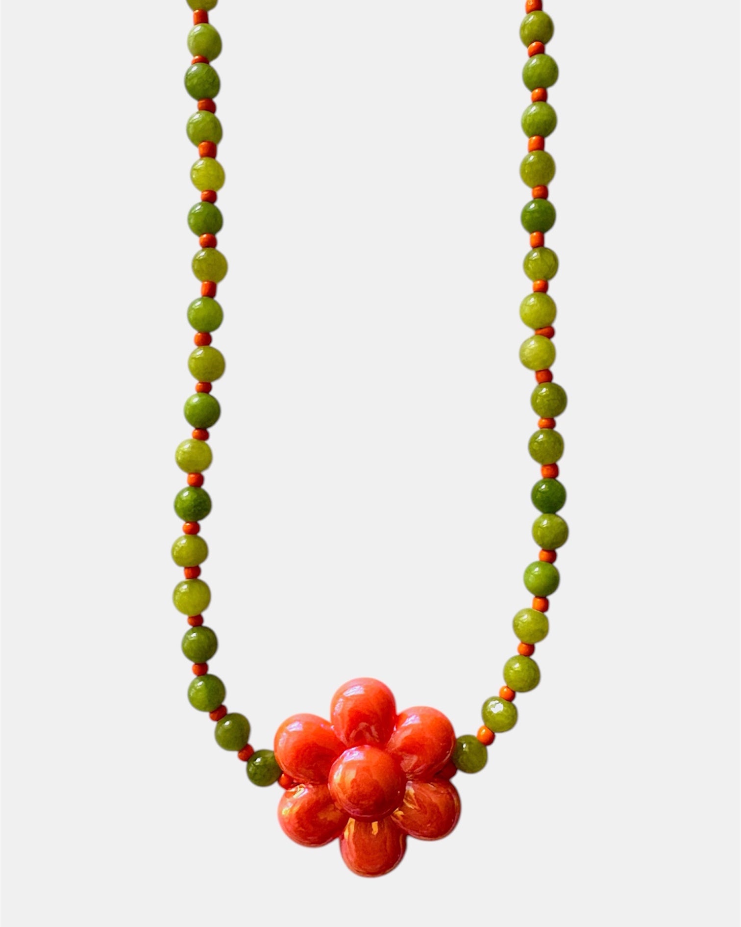Elegant green necklace with beads and ceramic flower charm, handmade jewelry inspired by nature with a fresh and artistic design