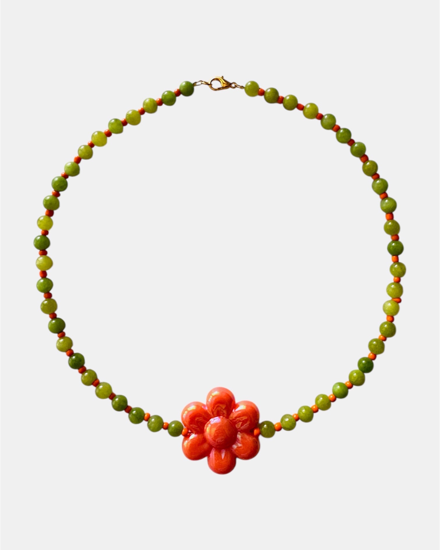 Elegant green necklace with beads and ceramic flower charm, handmade jewelry inspired by nature with a fresh and artistic design