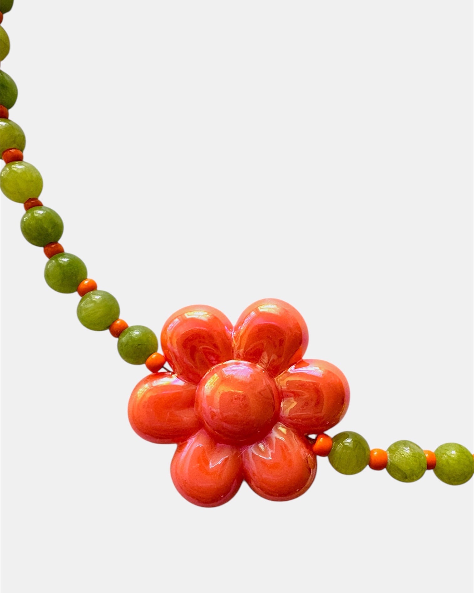 Elegant green necklace with beads and ceramic flower charm, handmade jewelry inspired by nature with a fresh and artistic design