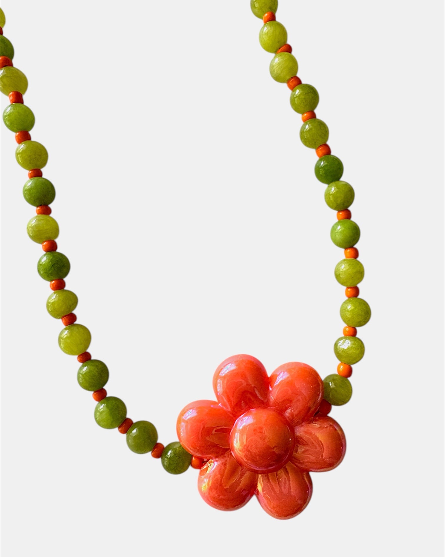 Elegant green necklace with beads and ceramic flower charm, handmade jewelry inspired by nature with a fresh and artistic design