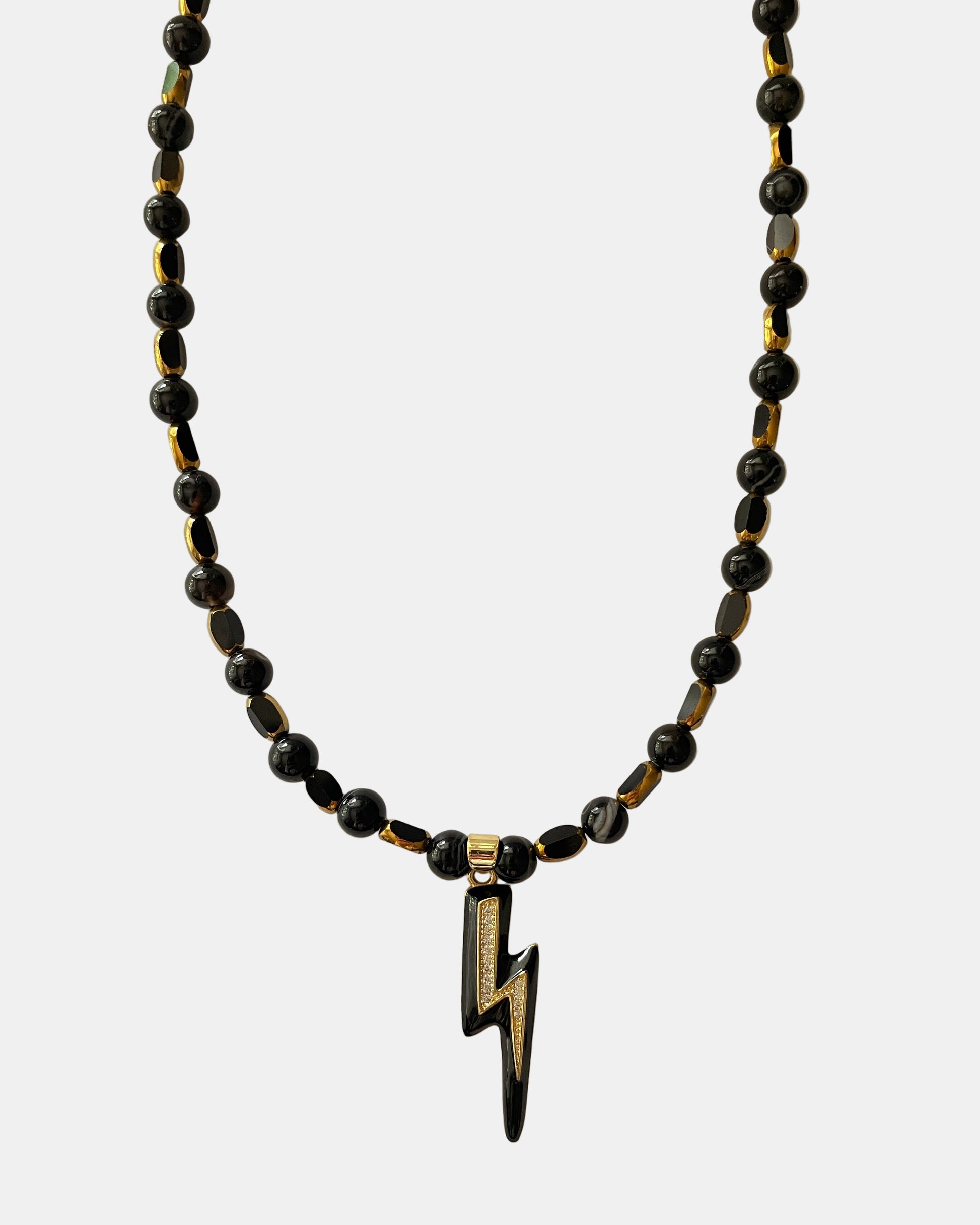Χειροποίητο μαύρο κολιέ με χρυσές λεπτομέρειες και κεντρικό μεταλλικό στοιχείο αστραπής.