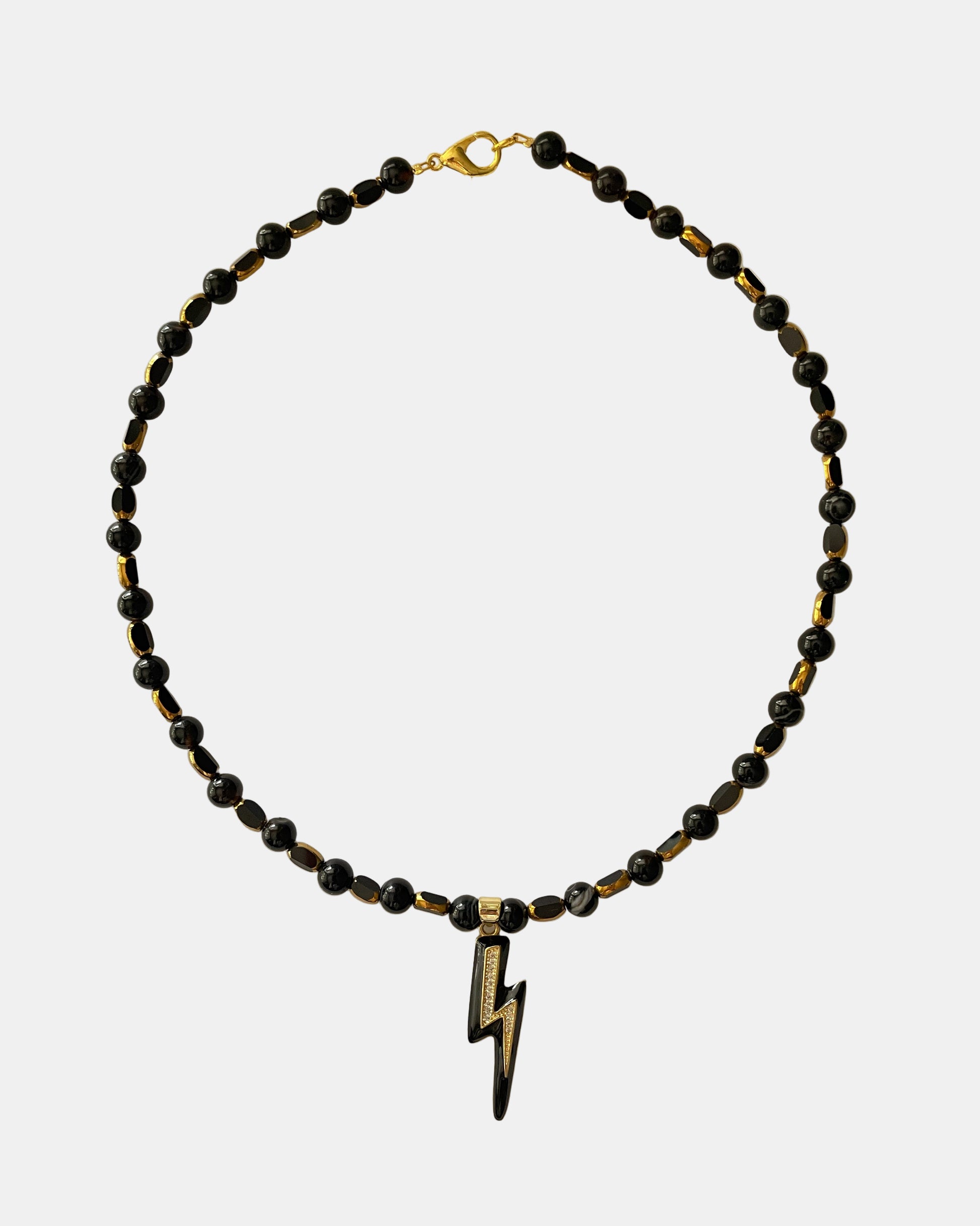 Χειροποίητο μαύρο κολιέ με χρυσές λεπτομέρειες και κεντρικό μεταλλικό στοιχείο αστραπής.