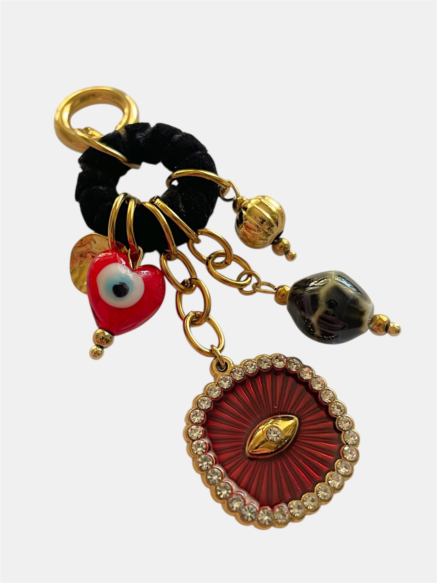Ζευγάρι εντυπωσιακών κρεμαστών σκουλαρικιών με χρυσές λεπτομέρειες, μαύρο υφασμάτινο κρίκο και κρεμαστά charms, όπως κόκκινη καρδιά με μάτι, μαρμαριζέ χάντρα και κεντρικό κόκκινο μοτίφ με στρας. Το σύνολο δημιουργεί μια boho–artistic αισθητική με έντονο χαρακτήρα και λάμψη.