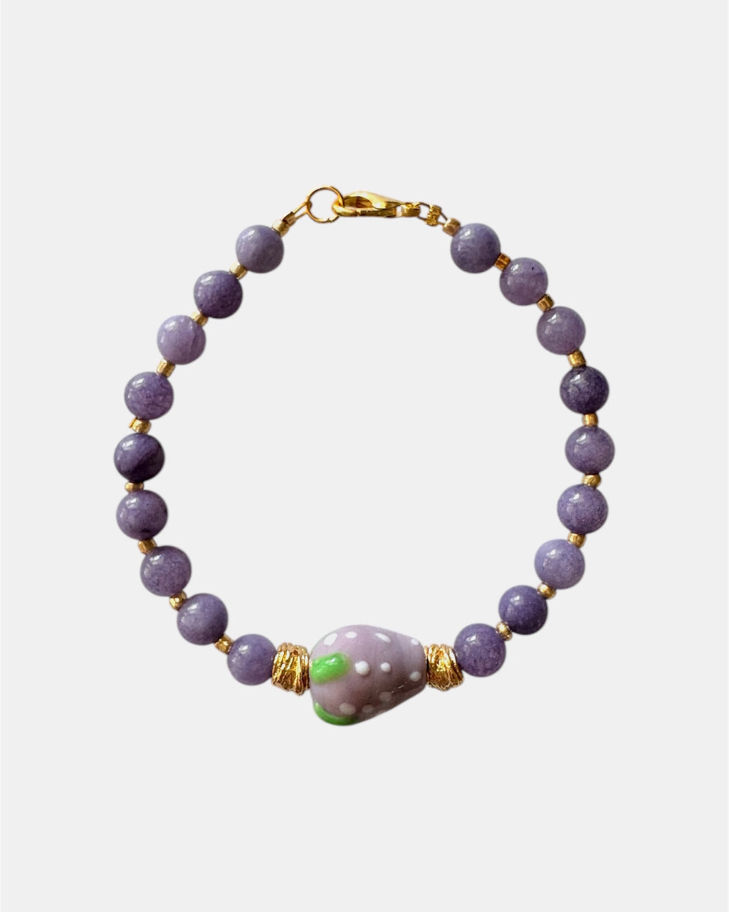 Purple beaded bracelet with a ceramic strawberry charm