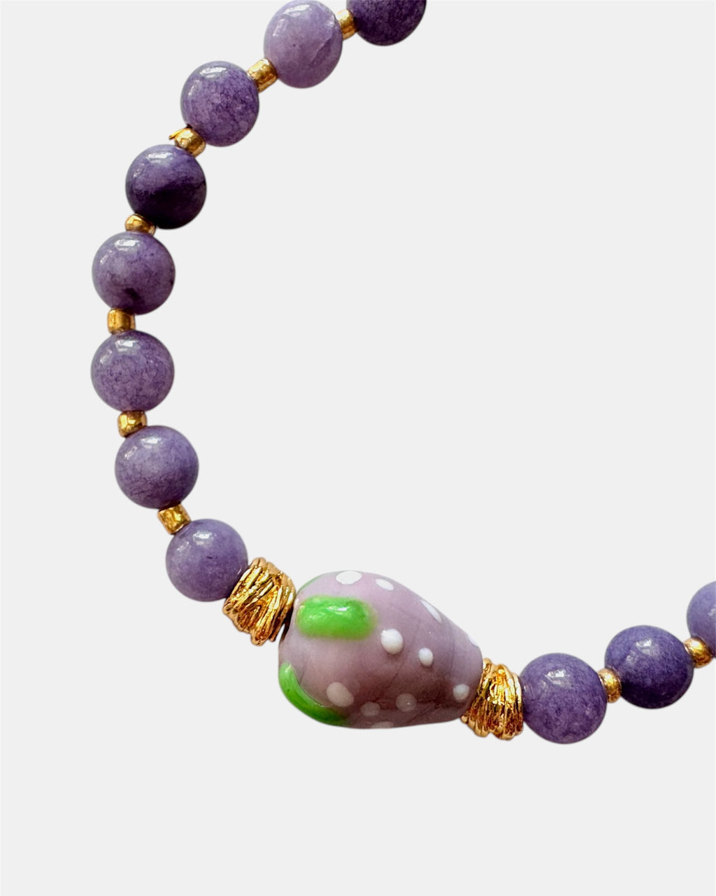 Purple beaded bracelet with a ceramic strawberry charm